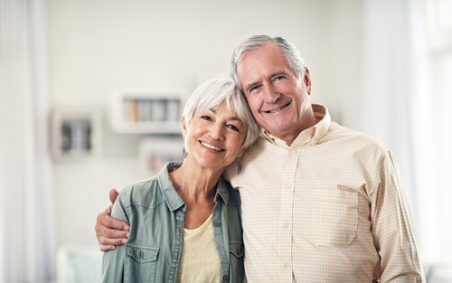 Smiling patients with dental implants standing dental office